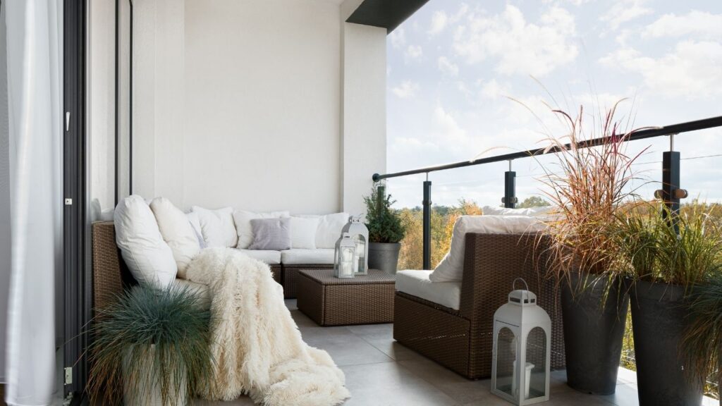 BROWN RATTAN CORNER SOFA POTTED PLANTS AND LANTERNS